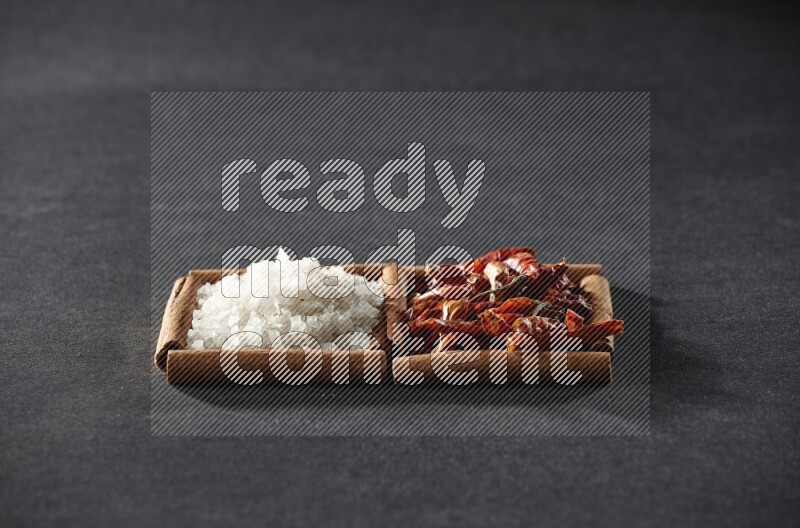 2 squares of cinnamon sticks full of chilis and salt on black flooring