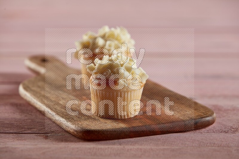 Vanilla mini cupcake topped with white chocolate curls on a wooden board