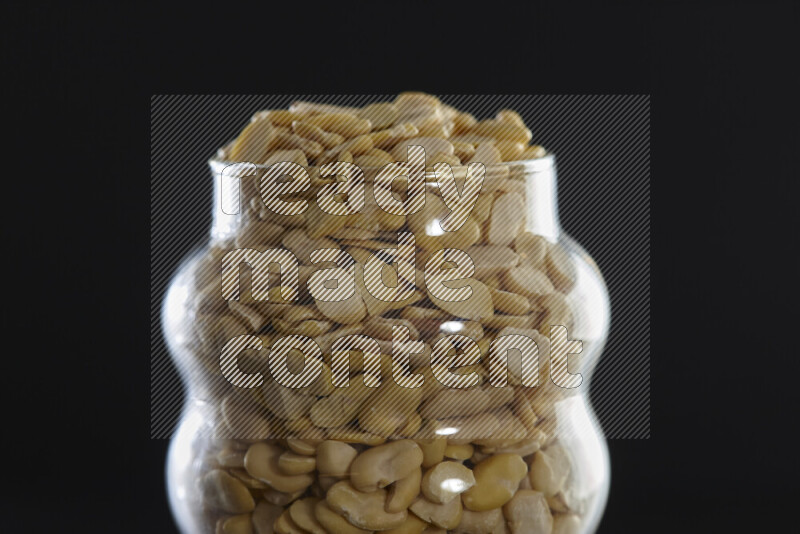 Crushed beans in a glass jar on black background