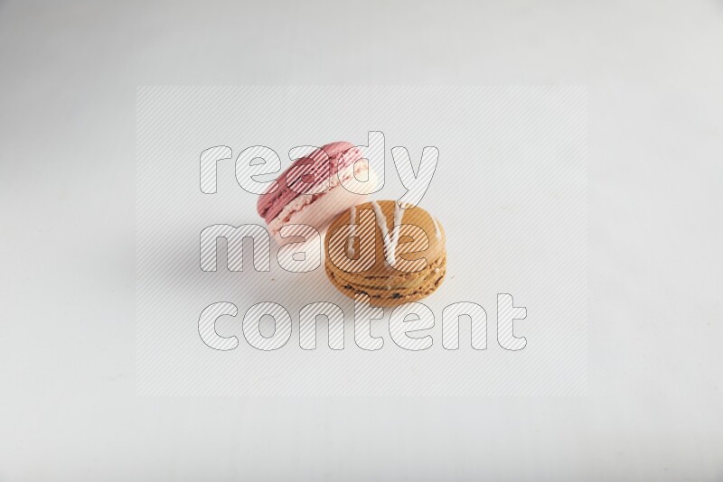 45º Shot of of two assorted Brown Irish Cream, and Pink Litchi Raspberry macarons on white background