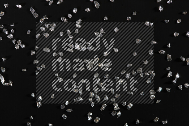 قطع زجاجية فضية لامعة متناثرة على خلفية سوداء