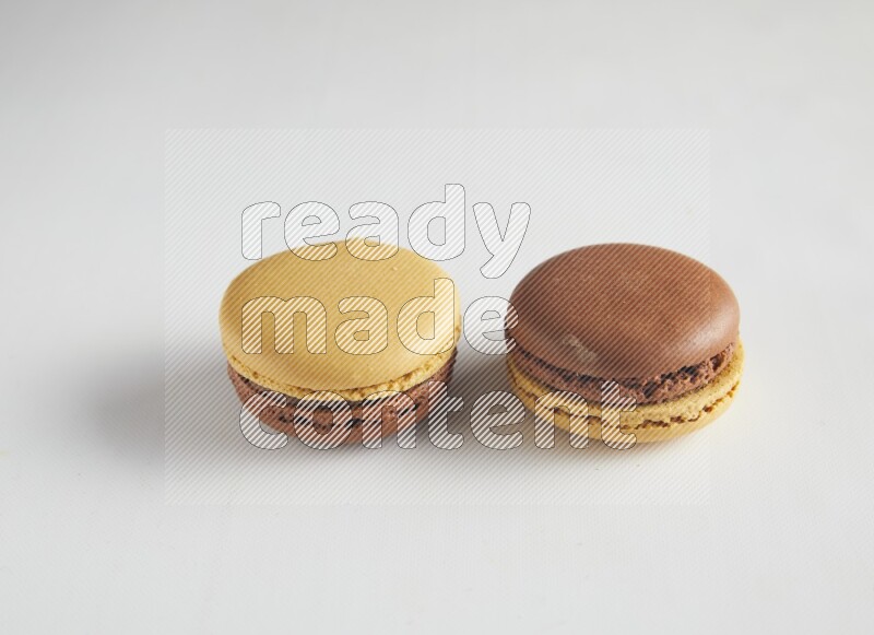 45º Shot of two Yellow and Brown Chai Latte macarons on white background