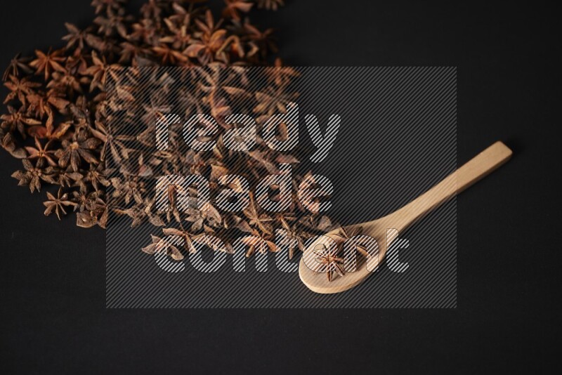 Star Anise in a wooden spoon and spreading on a black flooring
