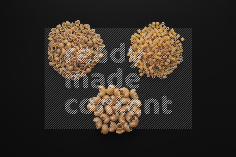 Different pasta types in bunches on black background