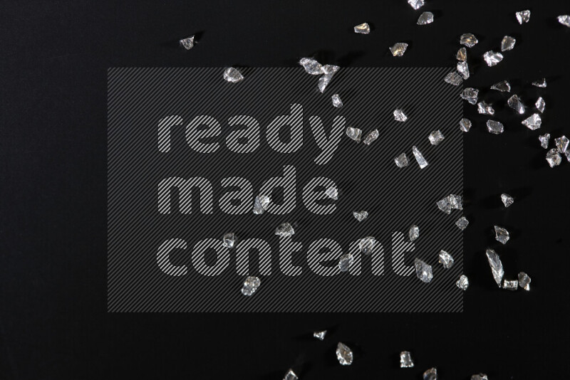 قطع زجاجية فضية لامعة متناثرة على خلفية سوداء