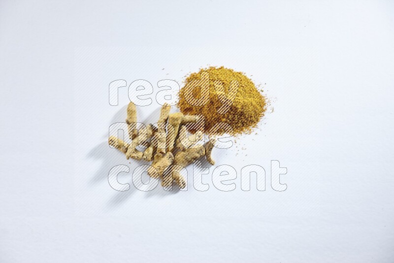 بودرة الكركم وأصابع الكركم المجففة على خلفية بيضاء