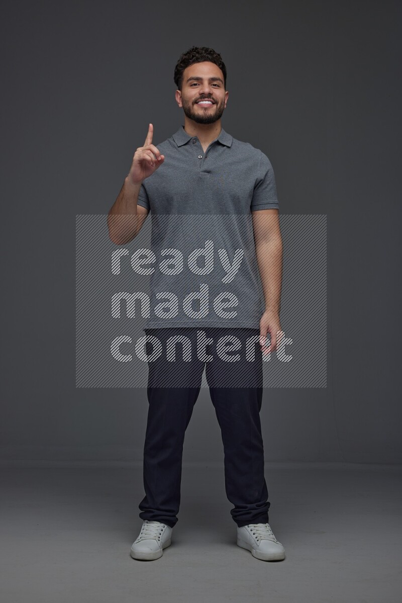 A man wearing casual standing and making multi hand gestures eye level on a gray background