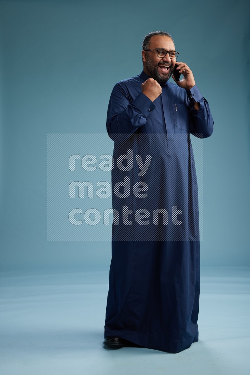 Saudi Man without shimag Standing talking on phone on blue background