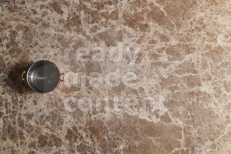 A small copper pot on beige marble background