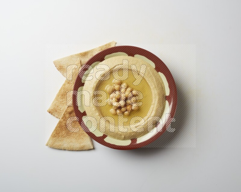 Hummus in a traditional plate garnished with roasted chickpeas  on a white background