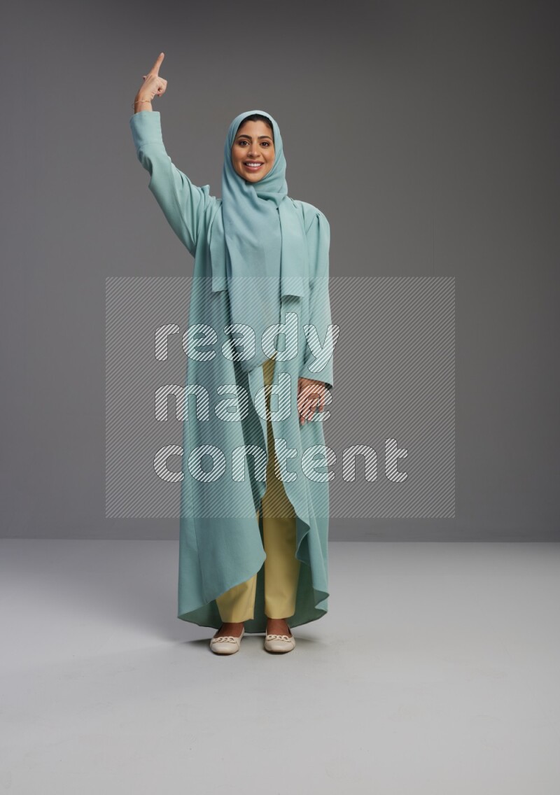 Saudi Woman wearing Abaya standing interacting with the camera on Gray background