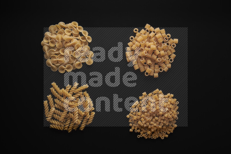 Different pasta types in bunches on black background