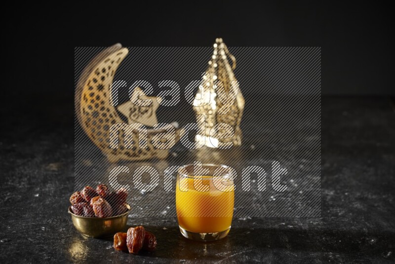 Dates in a metal bowl with qamar el din beside golden lanterns in a dark setup