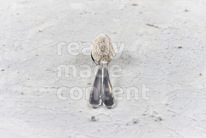 Two metal spoons full of onion powder on white background