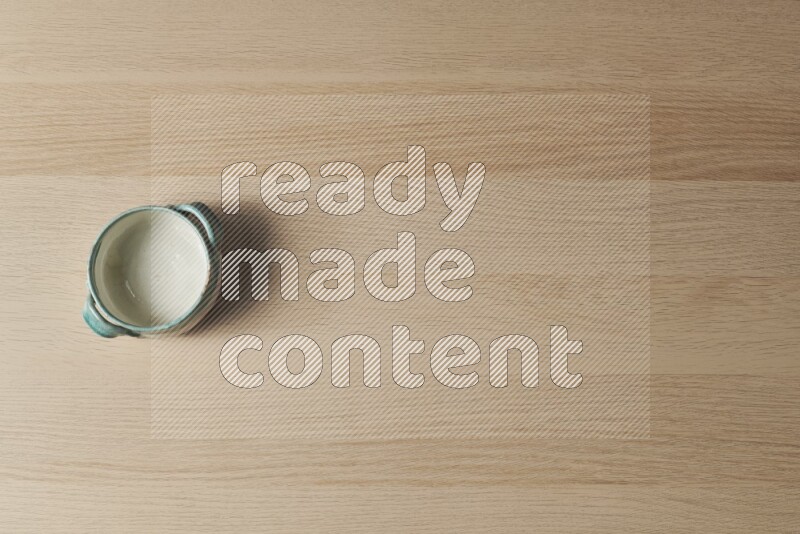 وعاء فخاري متعدد الألوان على خلفية خشبية فاتحة