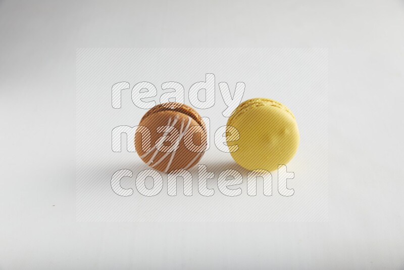 45º Shot of of two assorted Brown Irish Cream, and Yellow Lemon macarons on white background