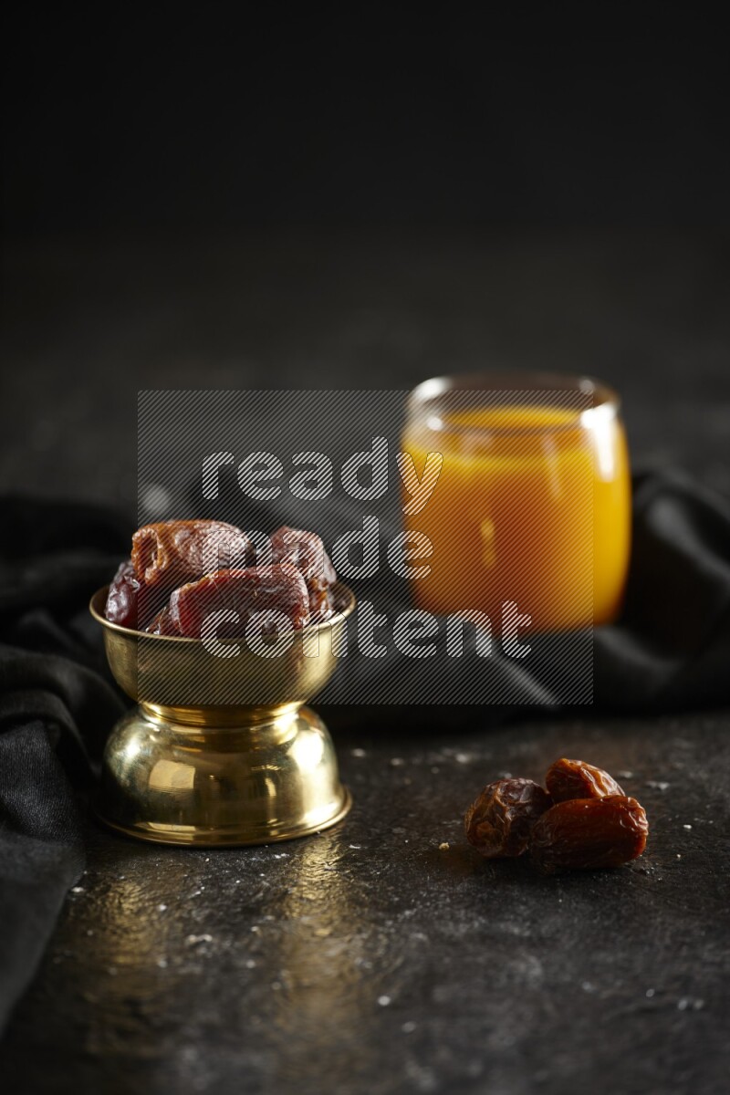 Dried fruits in a metal bowl with qamar eldin and a napkin in a dark setup
