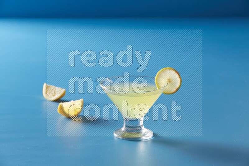 glass of lemon juice with lemon slice  on blue background