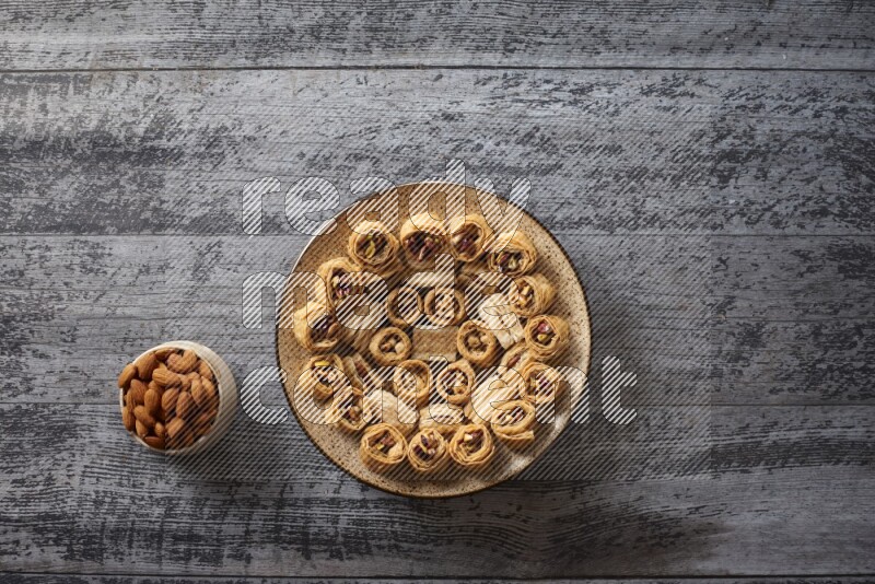 Oriental sweets in a pottery plate with nuts, coffee and honey in a dark setup