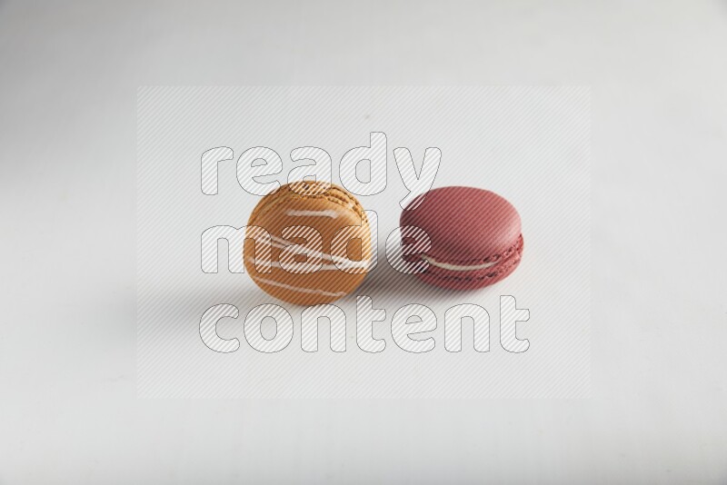 45º Shot of of two assorted Brown Irish Cream, and Red Velvet macarons on white background