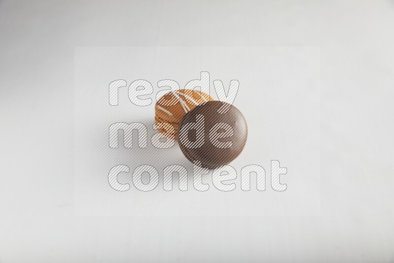 45º Shot of of two assorted Brown Irish Cream, and Brown Dark Chocolate macarons on white background