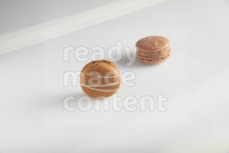 45º Shot of of two assorted Brown Irish Cream, and Brown Hazelnuts macarons on white background