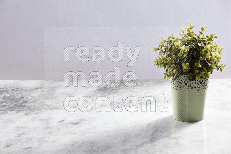 Artificial plant in green decorative pot on grey marble background