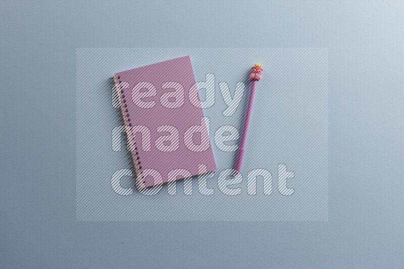 A purple notebook with different school supplies on blue background