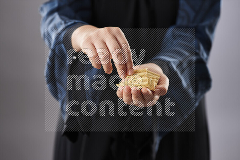 Woman in abaya holding different kinds of snacks in different positions