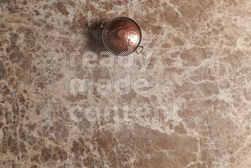 A small copper pot on beige marble background