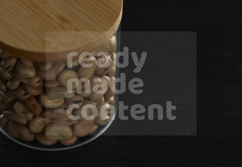 Fava beans in a glass jar on black background