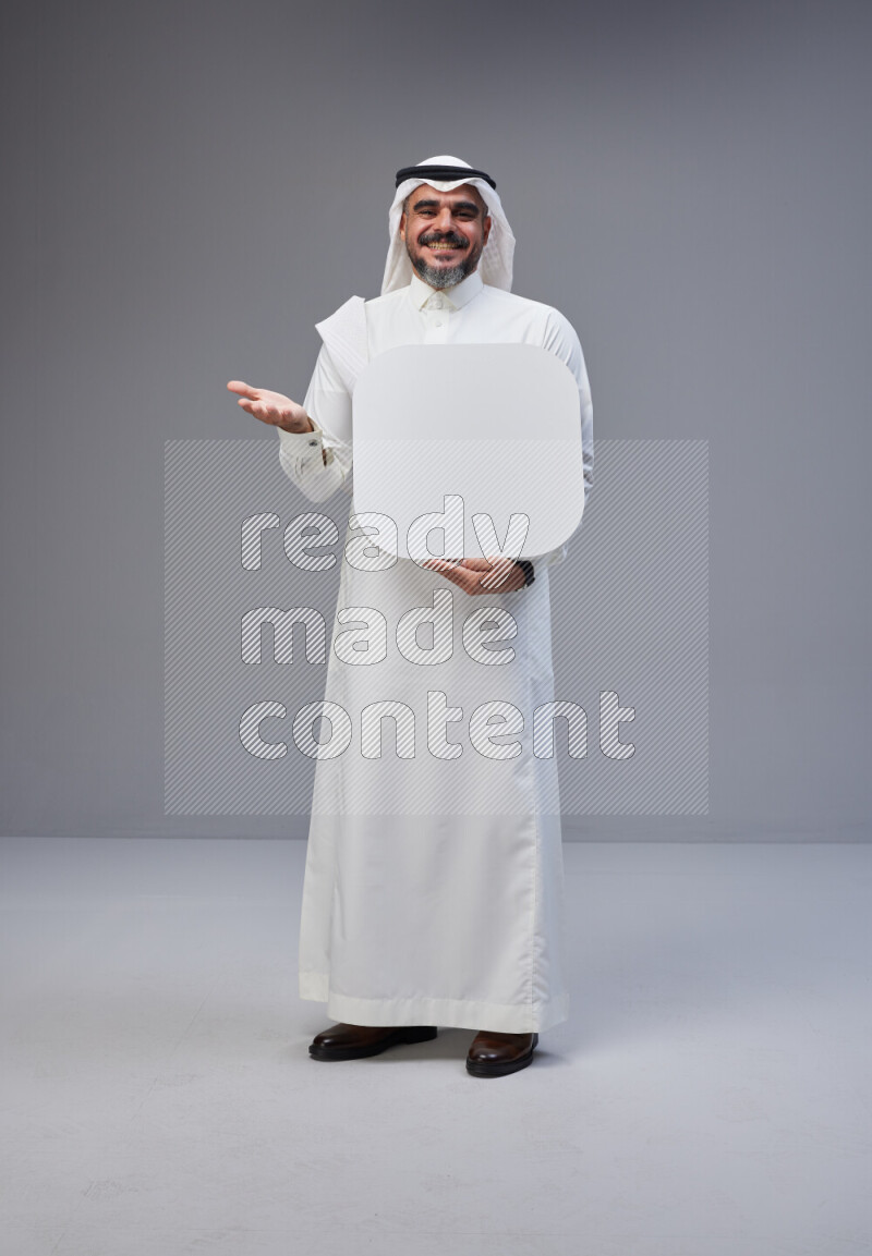 Saudi man Wearing Thob and white Shomag standing holding social media sign on Gray background