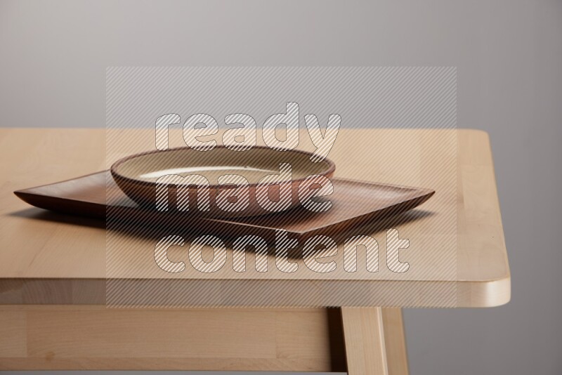 multicolored plate on a rectangular wooden tray on the edge of wooden table