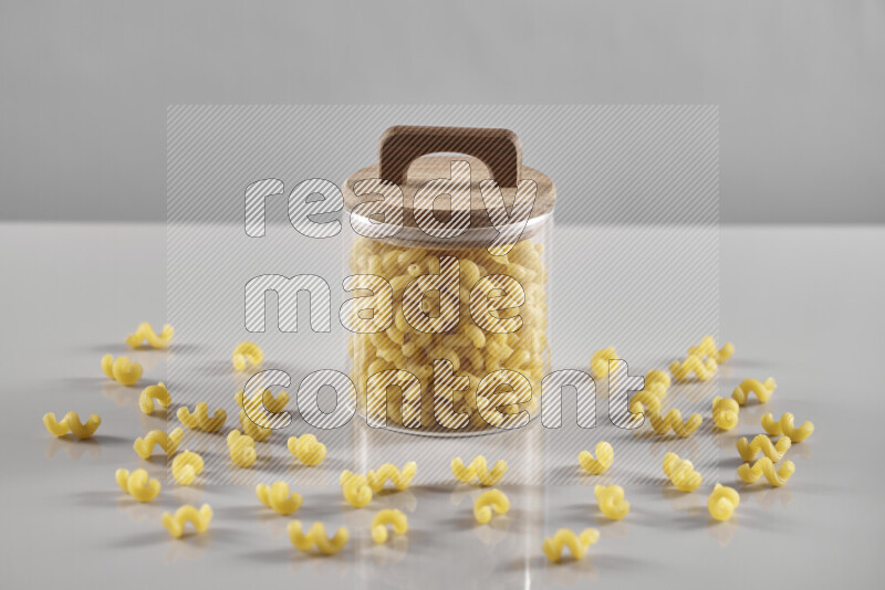 Raw pasta in a glass jar on light grey background