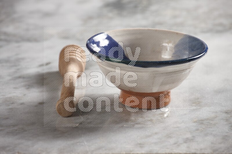 Multicolored pottery bowl with wooden honey dipper on the side on grey marble background