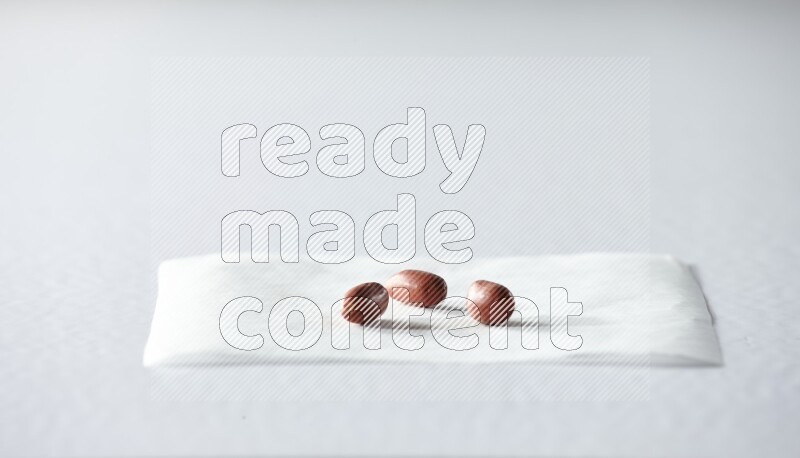 3 red skin peanuts on a piece of paper on a white background in different angles