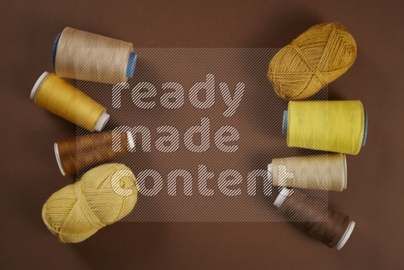 A yellow collection of sewing and tailoring tools arranged on a brown background
