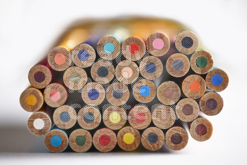 A close-up of the tips of colored pencils arranged in a bundle on white background