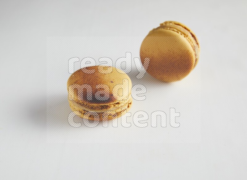 45º Shot of two Yellow Crème Brulée macarons on white background