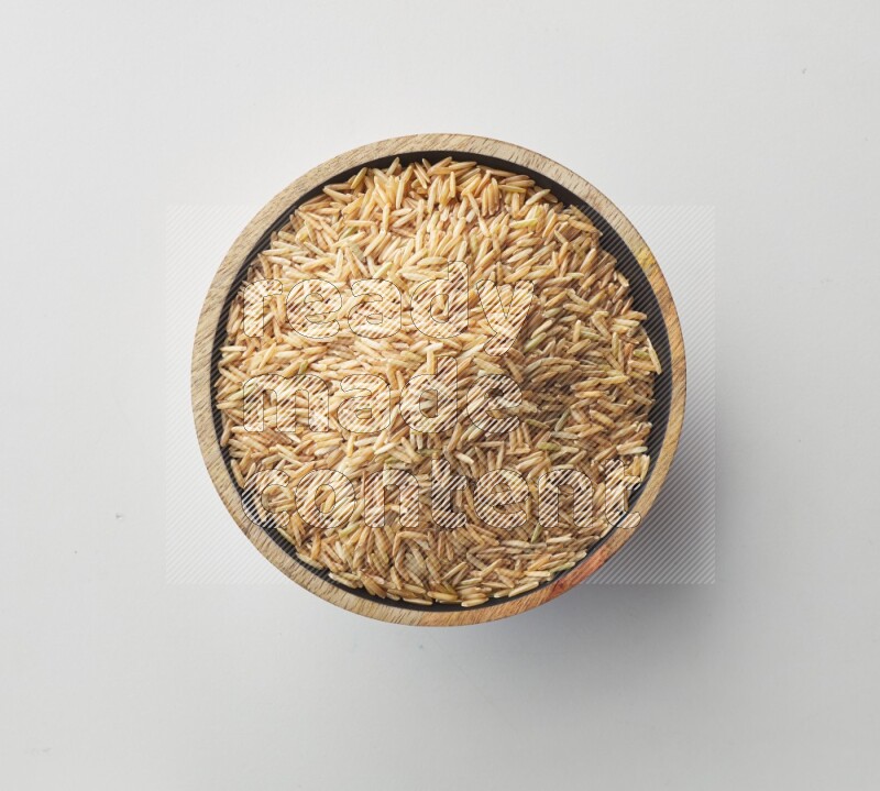 Top-view shot of long grain brown rice in a container on white background