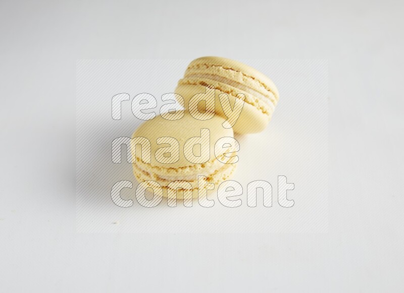 45º Shot of two Yellow Vanilla macarons on white background
