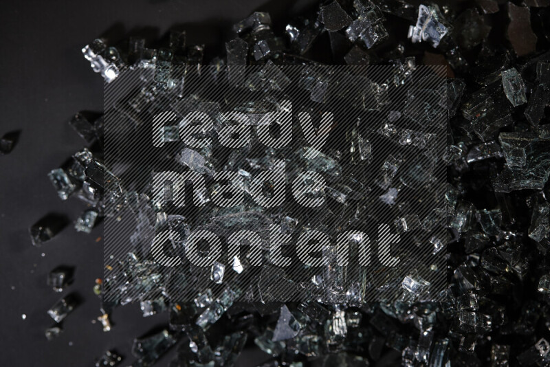 Transparent black fragments of glass scattered on a black background