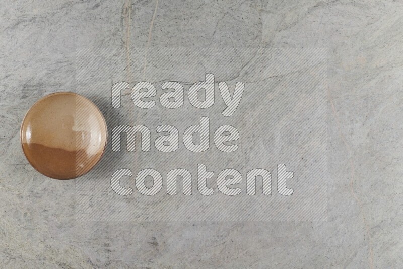 A beige pottery plate on grey marble background