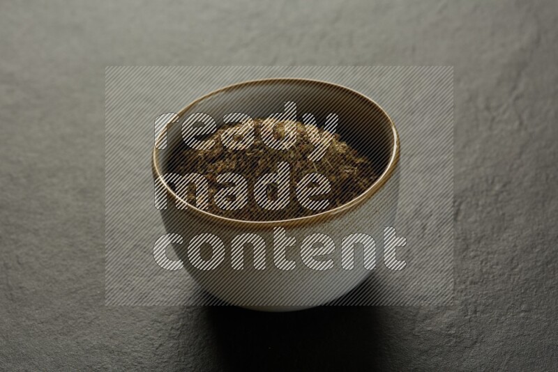 multi color round sauce bowl filled with herbs on grey textured countertop