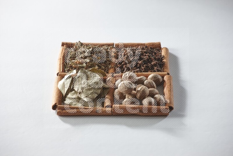 4 squares of cinnamon sticks full of bay laurel leaves, dried basil, cloves and nutmegs on white flooring