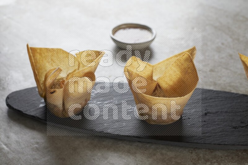 wonton cups with soy sauce ramkin on oval slate on grey textured counter top
