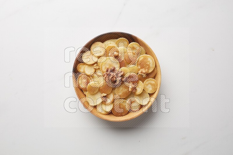 Top-view shot of walnut cereal pancakes in a round bowl on white background
