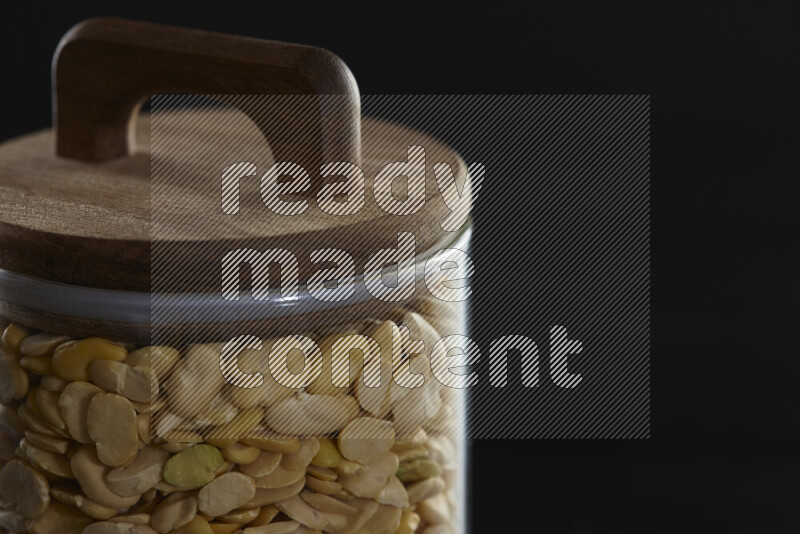 Crushed beans in a glass jar on black background