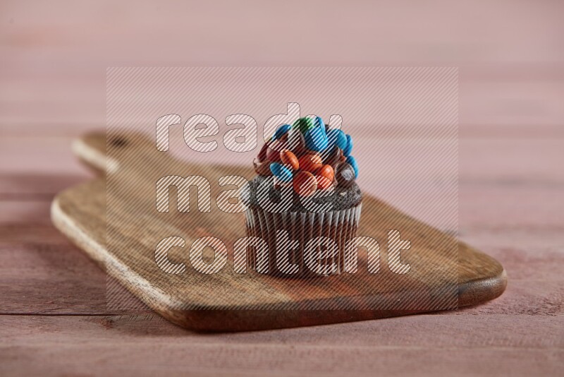 Chocolate mini cupcake topped with m&ms on a wooden board