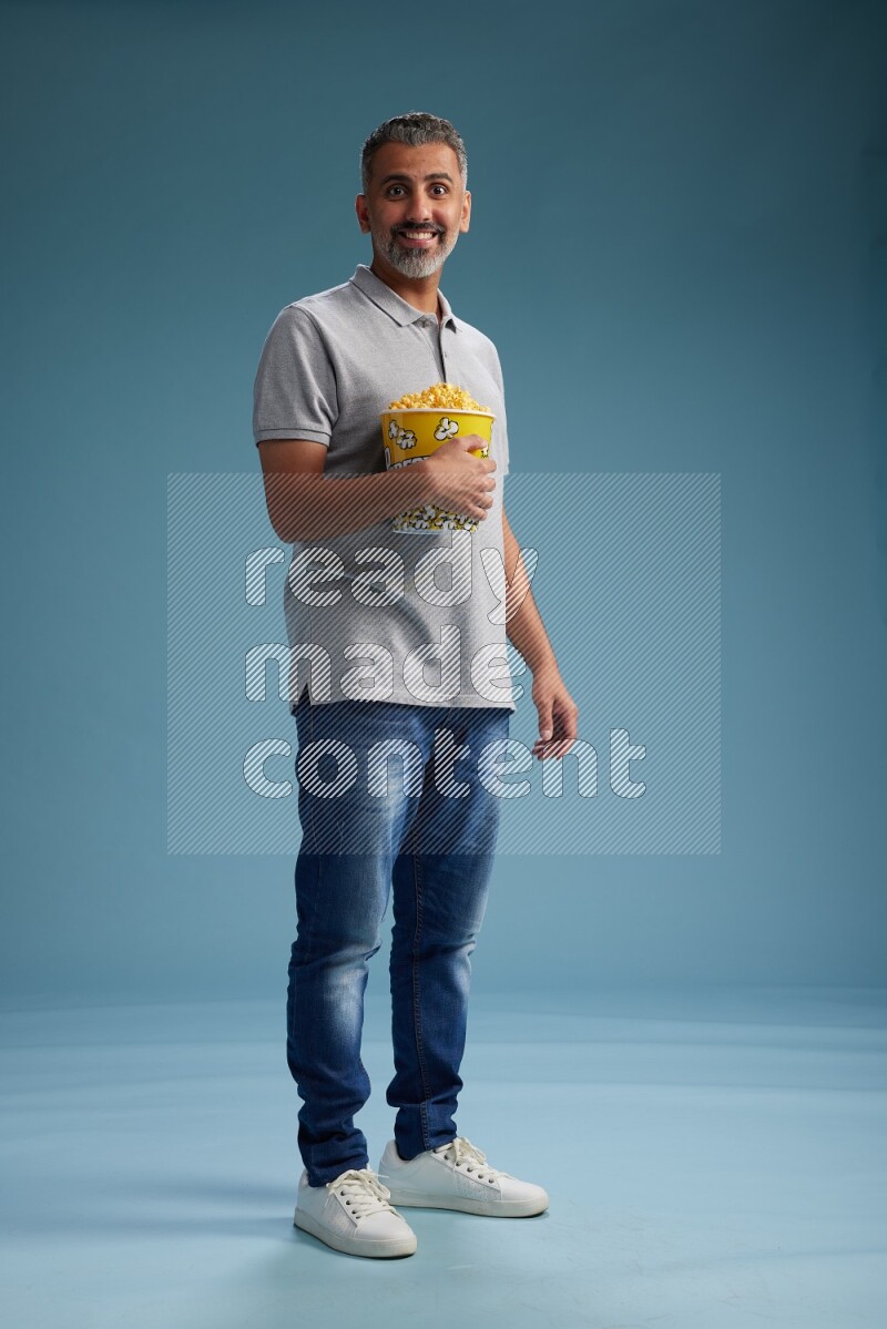 Man Standing eating popcorn on blue background